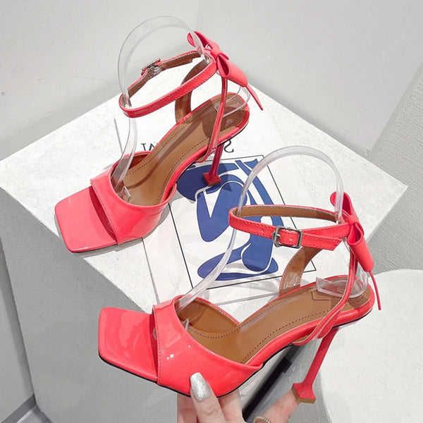 Sandalias de gladiador de charol rosa con punta abierta cuadrada y tacones altos y finos.